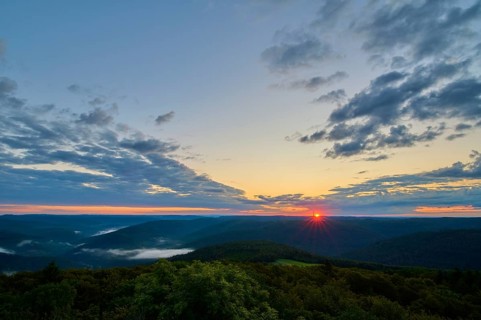 Sunrise over a forest landscape with vivid sky and clouds, warm colours of the morning,