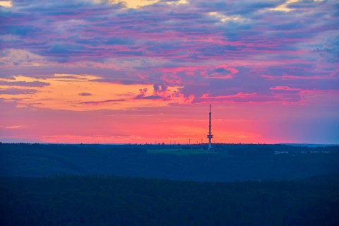 Dramatic sunrise on the horizon with a transmission mast, transmitter Reisenbach, as silhouette,
