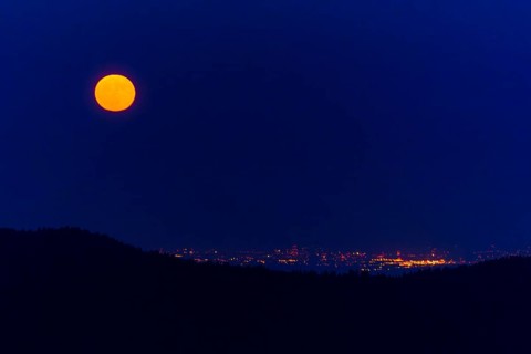 Full moon over a city with sparkling lights at night, full moon, strawberry moon 2025, Vosges,