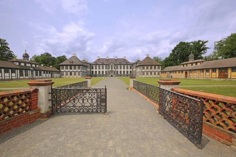 Entrance with decorated metal door to the baroque castle, wrought ironwork, decorations, garden