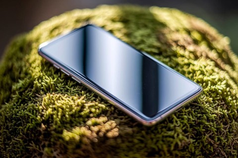 Modern smartphone on green moss. Elegant contrast between technology and nature in soft natural