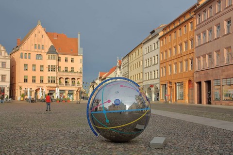 Historic houses with mood lighting on the market square, metal ball with reflection and inscription