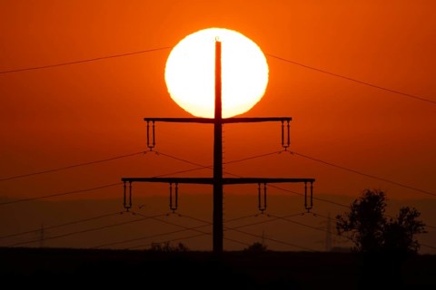 The sun rises behind an electricity pylon near Frankfurt am Main, Frankfurt am Main, Hesse, Germany