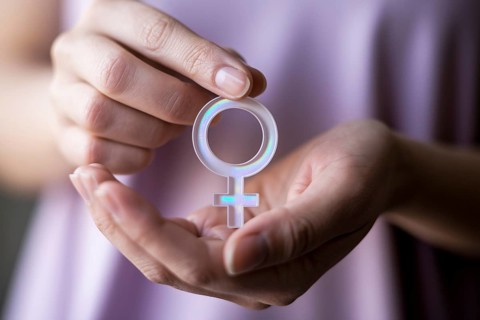 Woman's hands gently holding female gender symbol. A serene representation of femininity, identity,