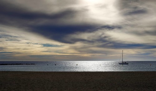 A sailboat anchored in calm waters under a dramatic cloudy sky, Tenerife, Canary Islands