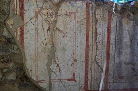 Weathered fresco with red decorative elements on ancient wall, Archaeological site, House of Beluga