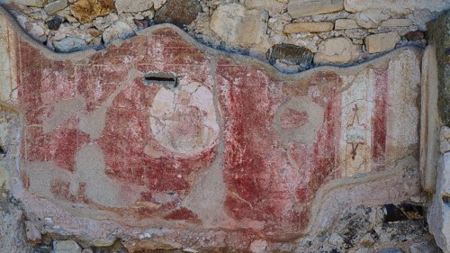 Decorated ancient wall fragment with red elements and traces of weathering, Archaeological Site,