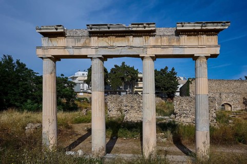 Ruins with three standing ancient columns and building remains in the background, Archaeological