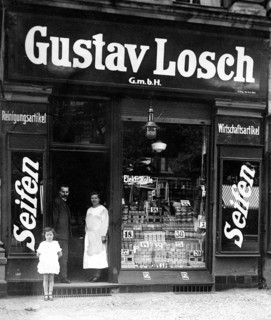 Soap shop, 1910, A man, a woman and a child stand in front of an old soap shop with a large sign