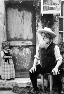 Granddaughter paints her smoking grandpa, 1910, An elderly man with a beard sits in front of a door