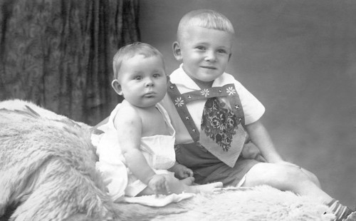 Two little boys on bed, 1930s, An older child holding a baby sitting on fur in a studio portrait,