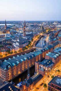Aerial view of the Speicherstadt Hamburg at blue hour with churches and Alster in the background,