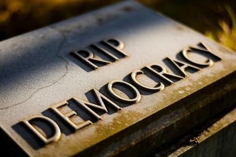 Old tombstone in ground with text RIP Democracy. Visual metaphor for the decline of democratic