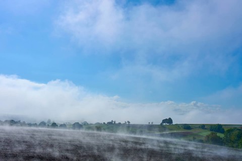 A wide landscape with fog, blue sky and trees in the distance, Schmachtenberg, Miltenberg,