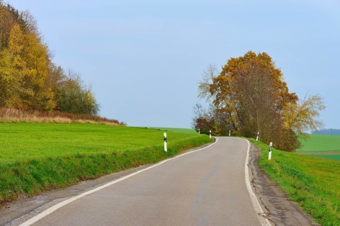 Winding country road between green fields and autumn trees, Hornbach, Walldürn, Odenwald,