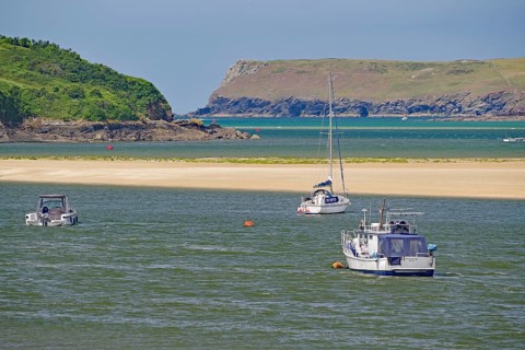 Boats on a river with green hills and rocky coast in the background, tides, Camel Trail, Padstow,