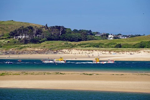 Two boats on the sea with green hills and a clear sky in the background, Padstow, Cornwall,