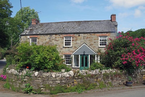 Stone house with lush garden and blooming flowers under a blue sky, idyllic cottage, Cornwall,