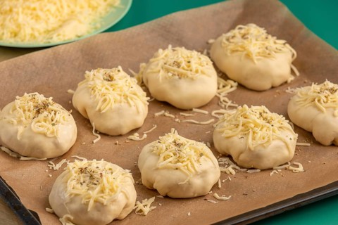 Raw pizza, balls with grated cheese and oregano on baking paper, ready for the oven