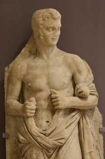 Marble sculpture of a half-naked man, draped in a cloth, classically leaning, Archaeological