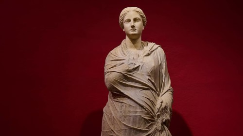 Marble statue of a woman in draped shawls, depicted against a red background, Archaeological
