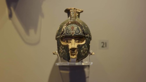 Ancient helmet, decorated, presented on a pedestal in an exhibition, depicting Hercules,