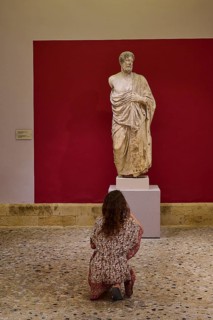 Woman observing an ancient marble statue of a man in a museum, Archaeological Museum, Kos Town,