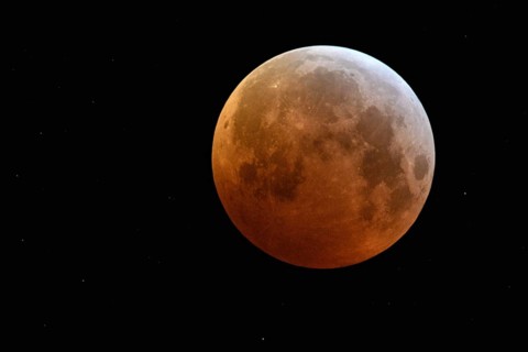Complete solar eclipse, full moon, blood moon, super moon surrounded by sparkling stars, rare event