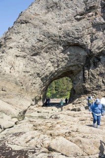 Large rock with a hole and people in the foreground, Hole in The Wall, Rialto Beach, Olympic