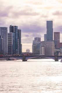 Modern cityscape with skyscrapers and a bridge across a river at sunset, London, United Kingdom,
