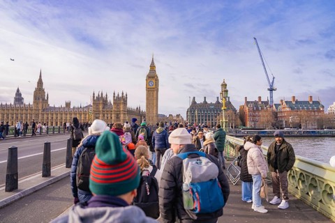 Tourists on a bridge looking at a famous clock tower on a clear day, London, United Kingdom, World