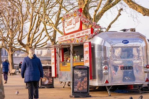 Silver food truck in a park surrounded by bare trees and pedestrians, London, United Kingdom, World