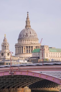 Bridge in front of a large cathedral with distinctive dome and towers, London, United Kingdom,
