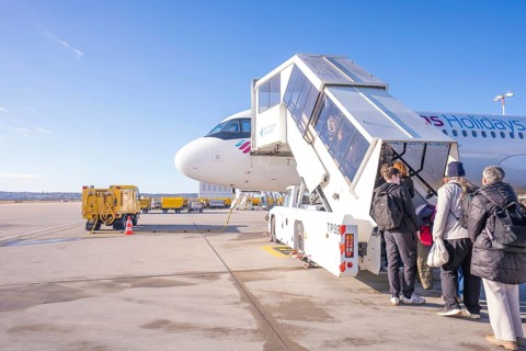 People board an airplane via a gangway, clear blue sky in the background, London, United Kingdom,