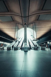 Bright, symmetrical escalator system in a modern station concourse, Canary Wharf Station, London,