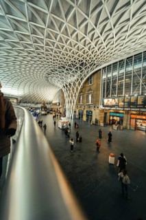 Large, modern train station with impressive glass roof and scattered travelers, King's Cross