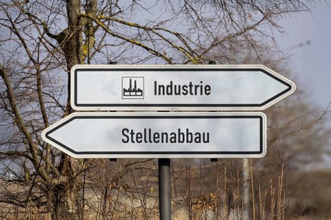 (photo montage) Directional arrows with the inscription INDUSTRY and JOB CUTS