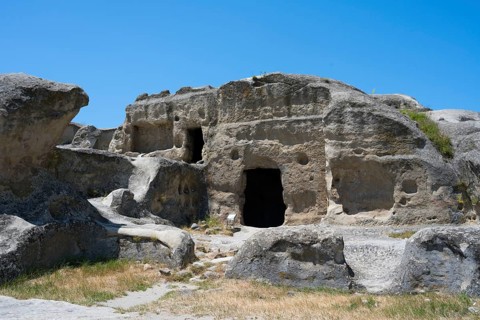 Ancient rock structure with several cave entrances in natural surroundings, Uplistsikhe cave town,