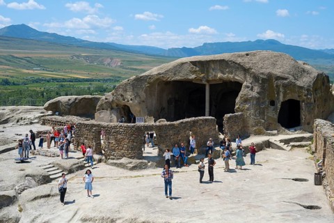 Tourists visit old caves and rock formations on a sunny day, Tamaris Darbasi, Tamara's Hall,
