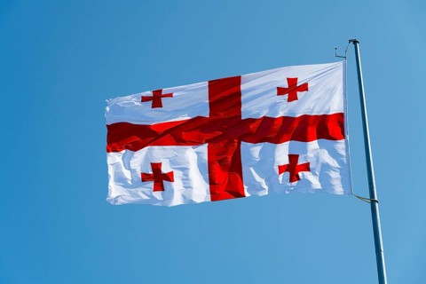 White flag with red crosses flying against a blue sky, flag of Georgia