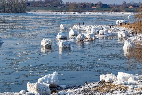 Many visitors look at the icebergs on the water of the Elbe and on the banks of the Elbe Island