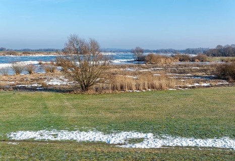 Icy riverbanks of the Elbe and remnants of snow in the foothills of the Elbe on a clear winter day.