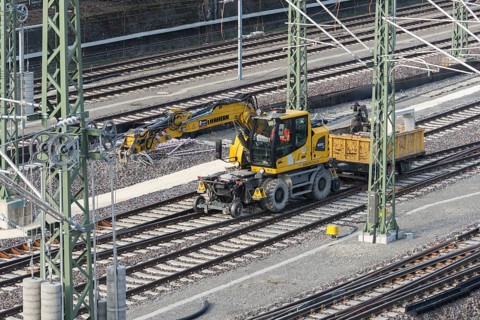 A yellow rail vehicle on a railway line surrounded by construction site equipment, Untertürkheim