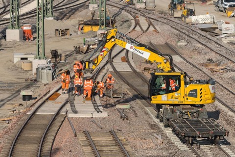 Construction workers wearing orange safety clothing during track repairs on a construction site,