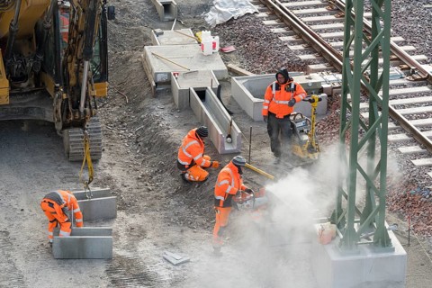 Construction workers in protective clothing carry out work on rails, accompanied by construction