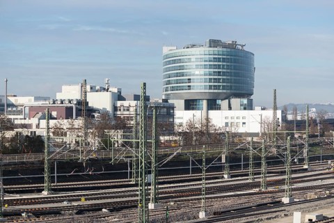 Modern building in an industrial area with railroad tracks in the foreground under clear skies,