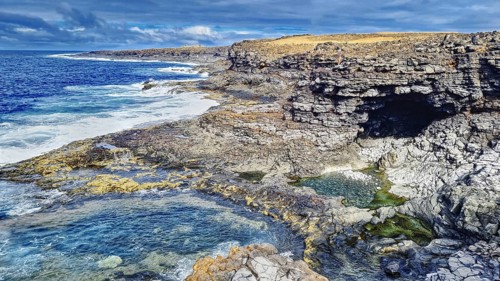Rugged coastal landscape with rocks and a grotto. Waves hit the rocky shoreline, Yaiza Lanzarote
