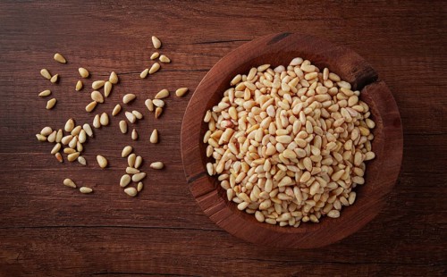 Peeled pine nuts, in a wooden bowl, on a wooden table, close-up, no people