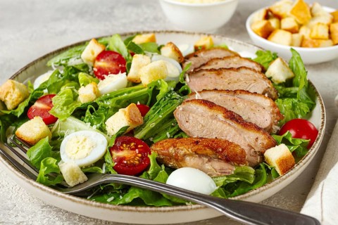 Caesar salad, with duck breast, on a light plate, on a light background, homemade, no people