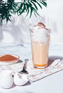 Eggnog drink, egg yolk, in a glass, with cream and cinnamon, sunlight